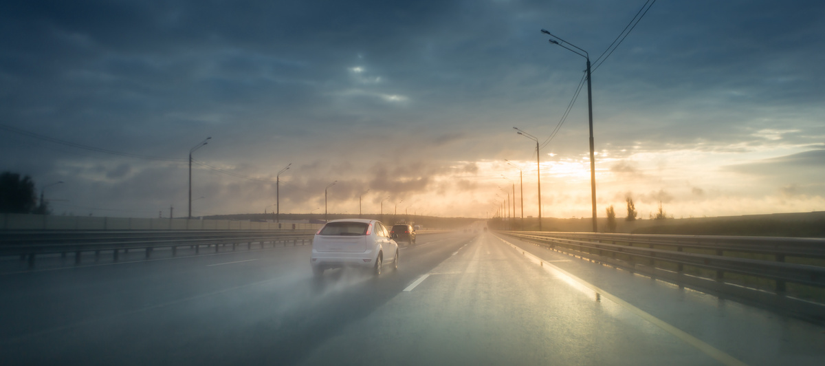 Conduite sur une route mouillée avec un coucher de soleil nuageux mais lumineux, des conditions climatiques idéales pour un pneu hiver