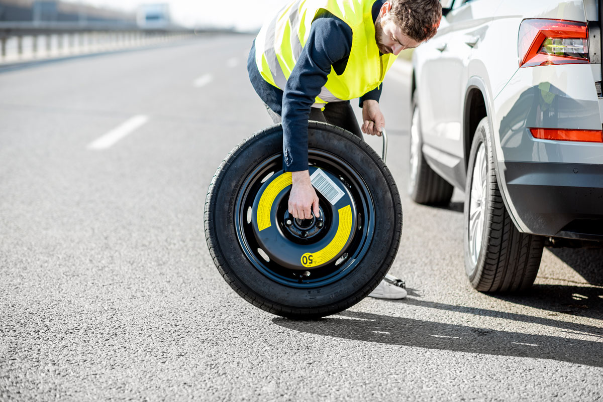 Homme qui tient une roue de secours dans sa main pour l'installer