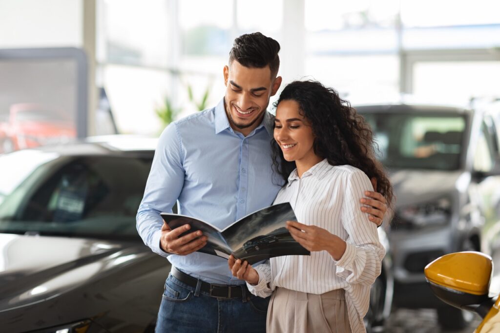 Un couple qui choisit une voiture neuve et est en train de la configurer sur catalogue